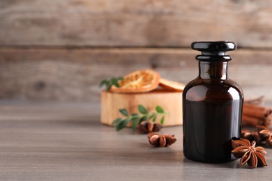 Photo of Anise essential oil and spice on wooden table. Space for text