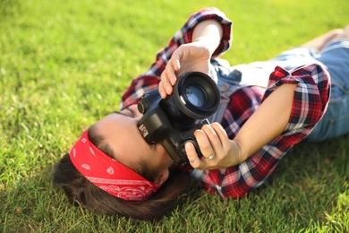 Photo of Young photographer taking picture with professional camera on green grass