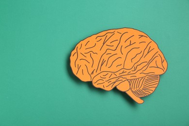Photo of Paper cutout of human brain on turquoise background, top view. Space for text