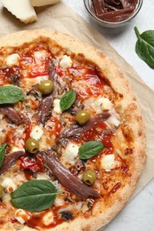 Tasty pizza with anchovies and ingredients on white table, flat lay