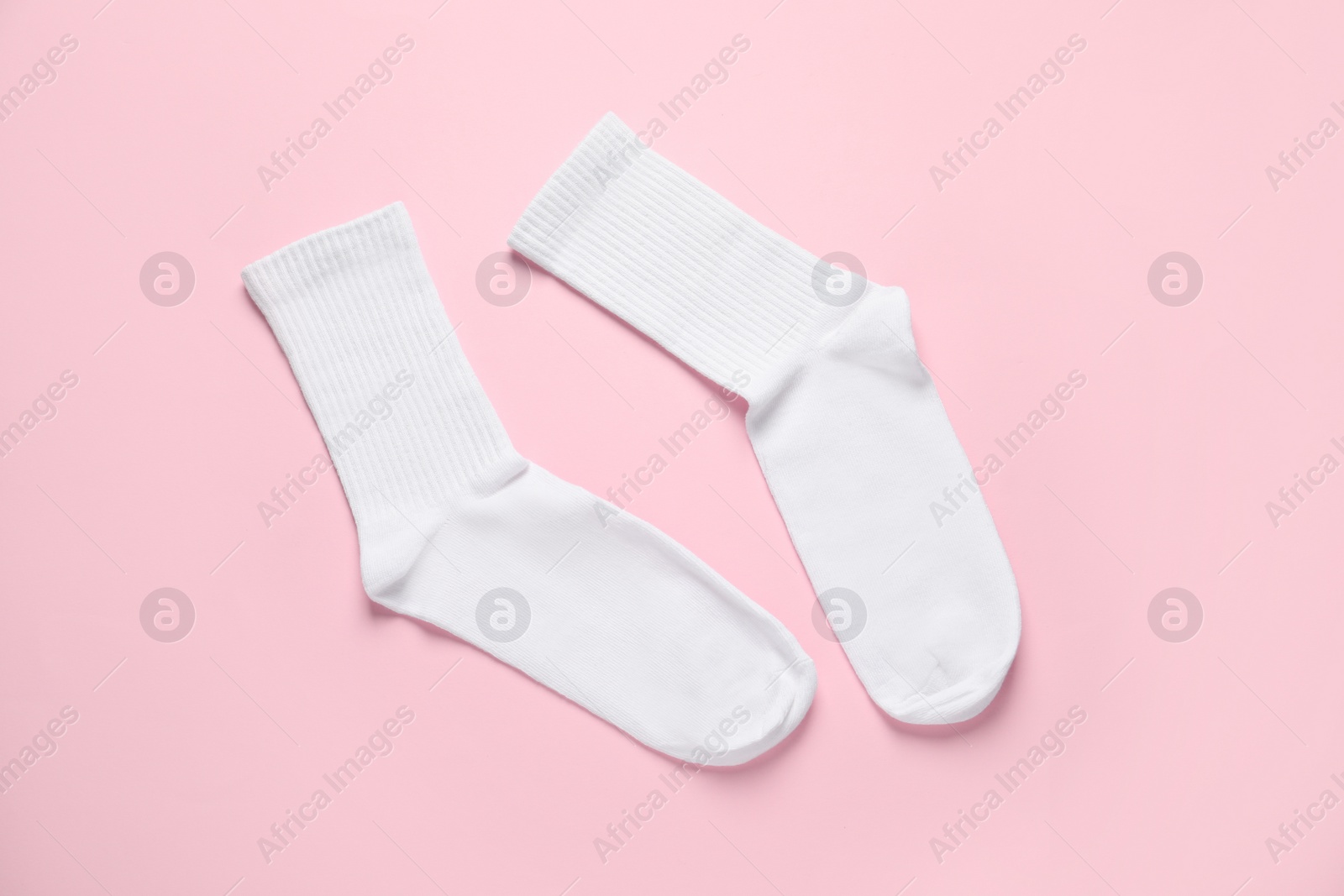 Photo of Pair of white socks on pink background, flat lay