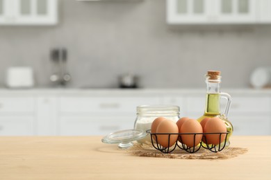 Photo of Eggs, flour and oil on wooden table in kitchen. Space for text