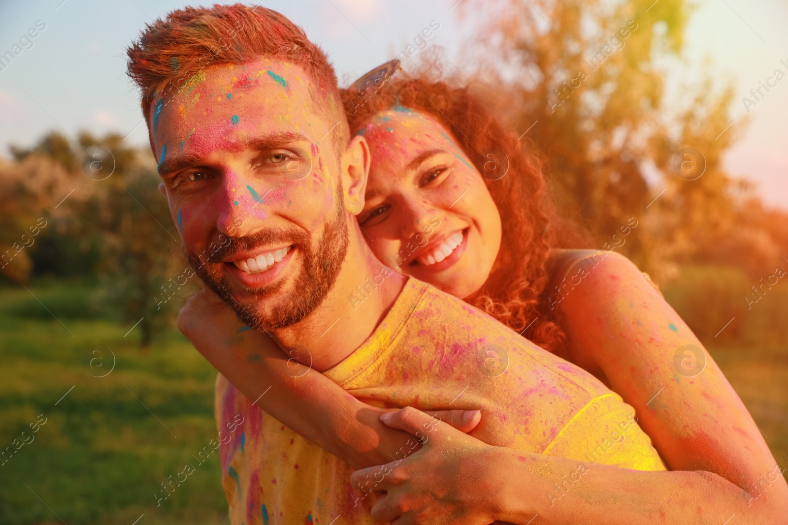 Photo of Happy couple covered with colorful powder dyes outdoors. Holi festival celebration