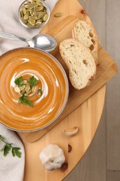 Delicious pumpkin soup served on wooden table, flat lay