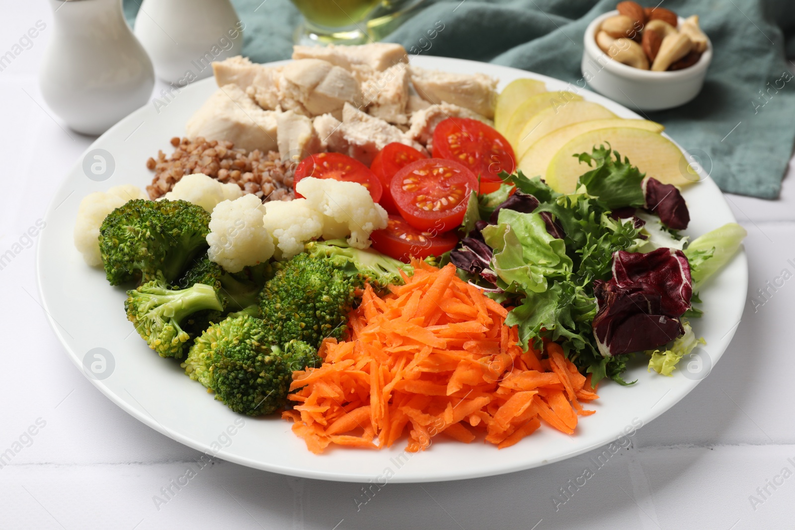 Photo of Balanced diet and healthy foods. Plate with different delicious products on white tiled table, closeup