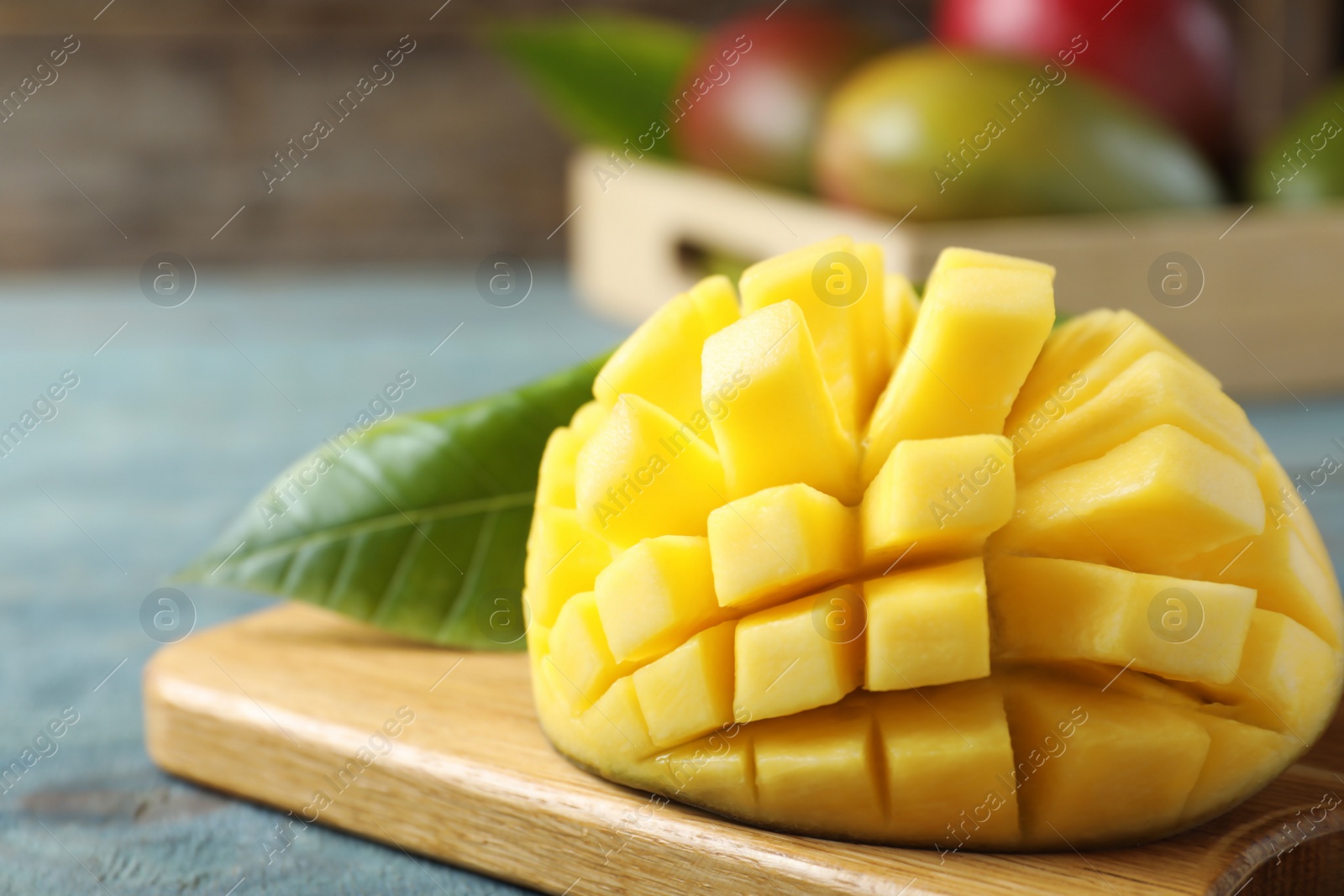 Photo of Cut fresh ripe mango on blue wooden table, closeup