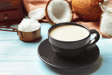 Photo of Delicious coffee with organic coconut oil on blue wooden table