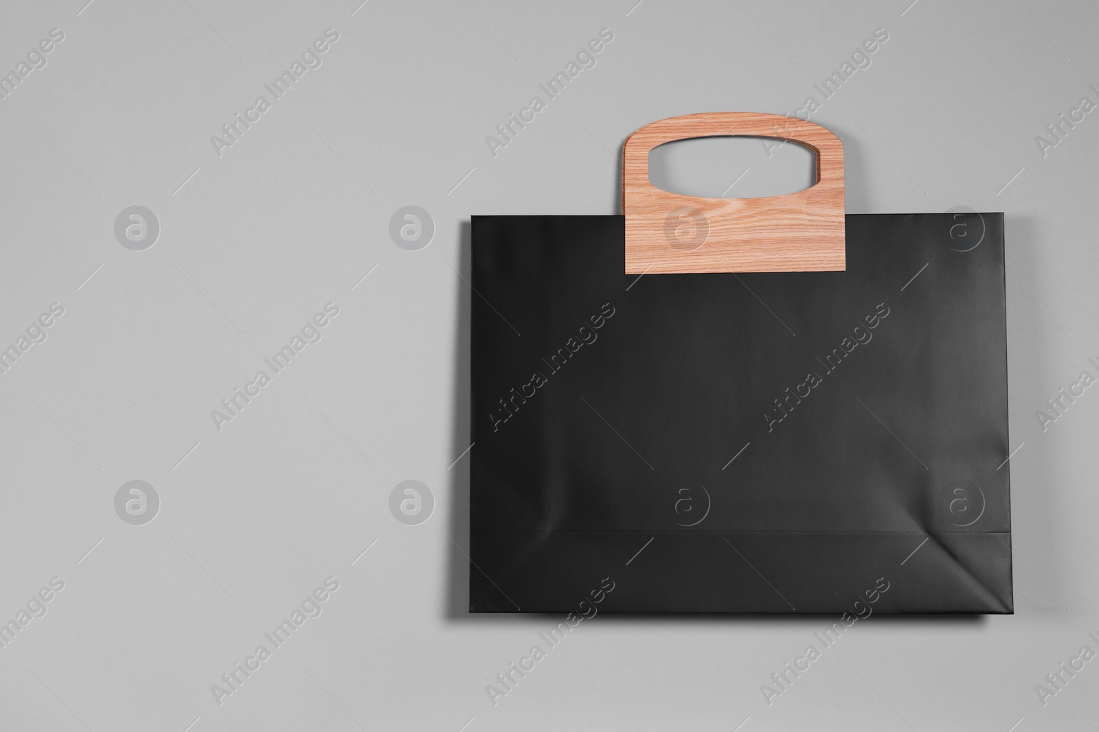 Photo of One black paper shopping bag on grey background, top view. Space for text