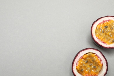 Photo of Halves of fresh ripe passion fruit (maracuya) on grey background, flat lay. Space for text