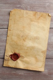 Photo of Sheet of old parchment paper with wax stamp on wooden table, top view