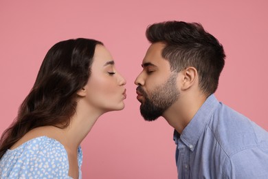 Photo of Cute young couple kissing on pink background