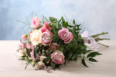 Photo of Beautiful bouquet with roses on light wooden table