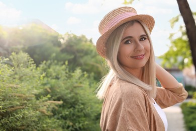 Portrait of beautiful woman in straw hat outdoors on sunny day