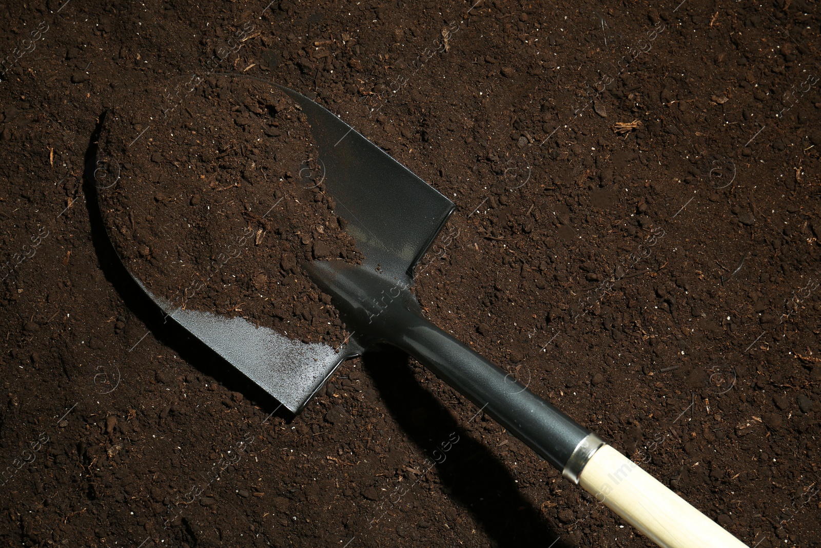 Metal shovel on fertile soil, top view. Gardening tool Photo of Metal shovel on fertile soil, top view. Gardening tool