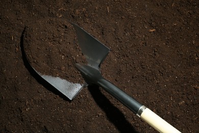 Photo of Metal shovel on fertile soil, top view. Gardening tool