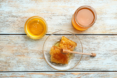 Photo of Different types of honey on light blue wooden table, flat lay