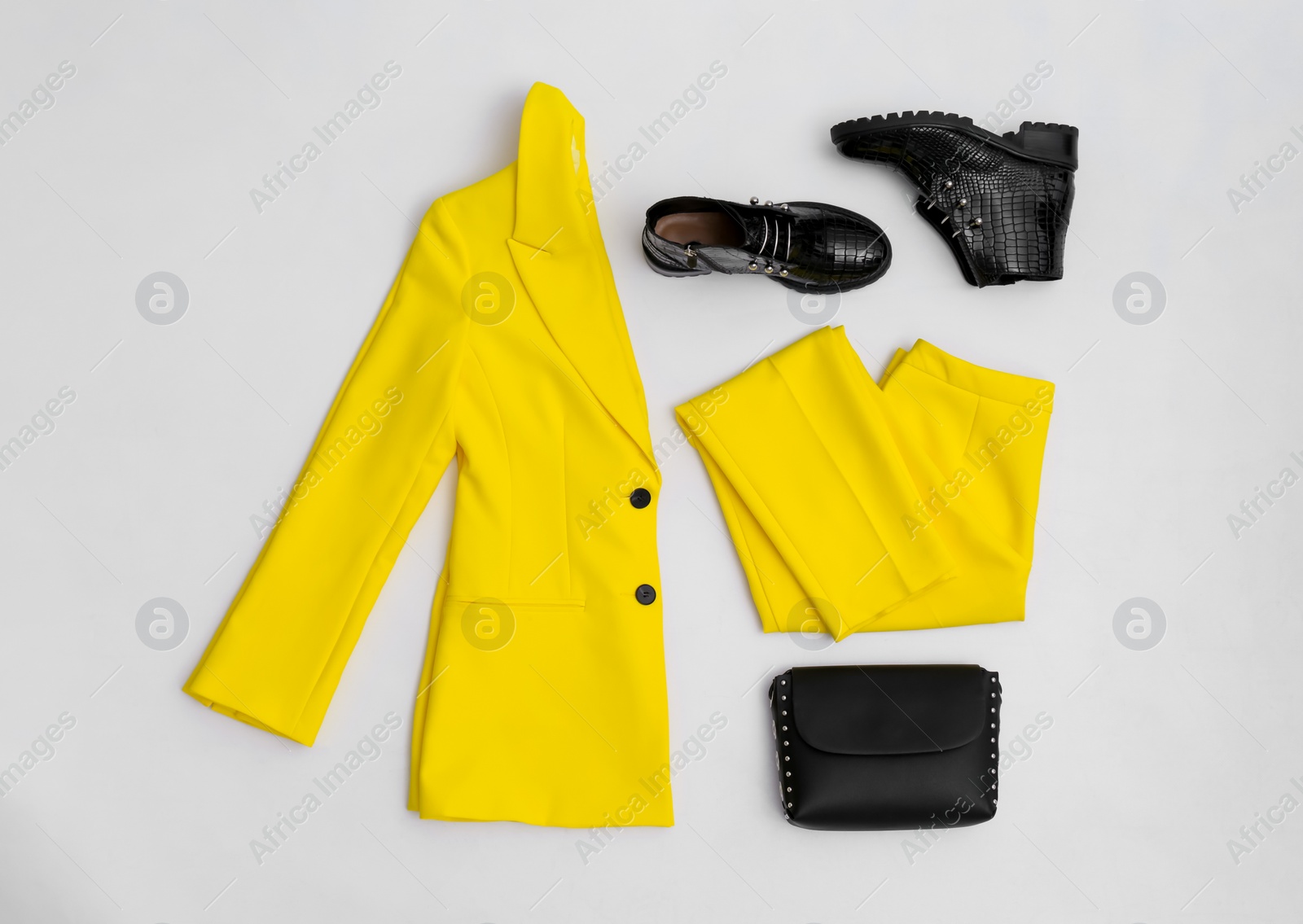 Photo of Stylish ankle boots, handbag and yellow office suit on white background, top view