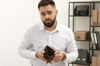 Upset man with empty wallet in office