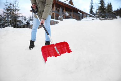 Man cleaning snow with shovel outdoors on winter day, closeup