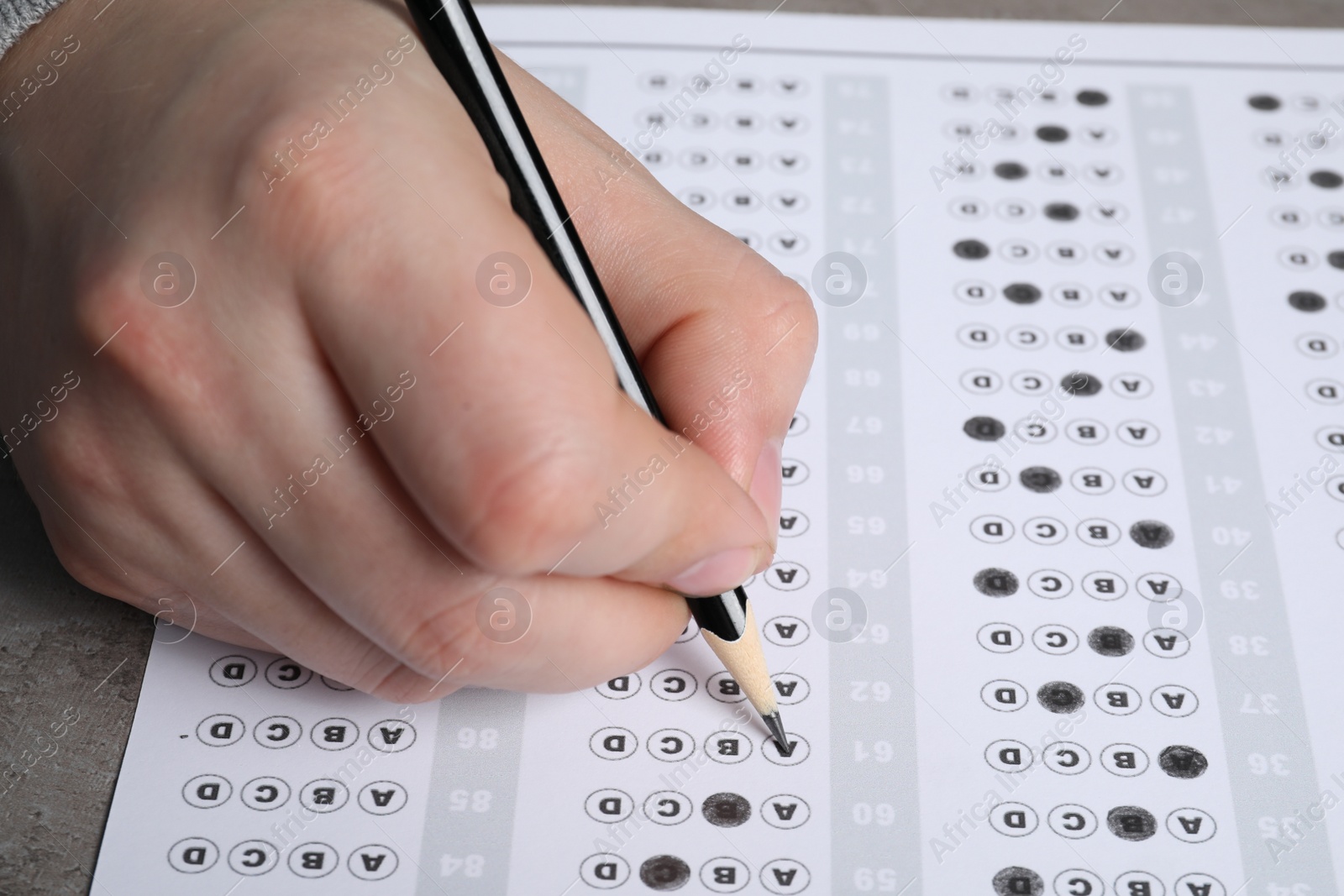 Photo of Student filling answer sheet at table, closeup. Passing exam