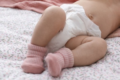 Photo of Little baby in diaper on bed, closeup