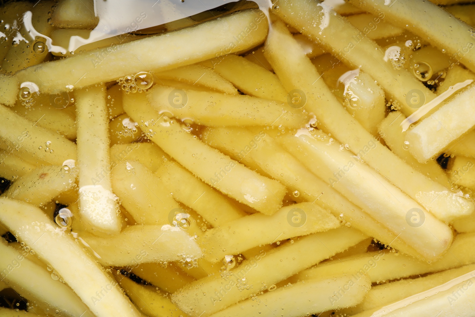 Photo of Cooking delicious french fries in hot oil, closeup