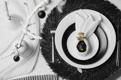 Festive table setting with bunny ears made of black egg and napkin, above view. Easter celebration