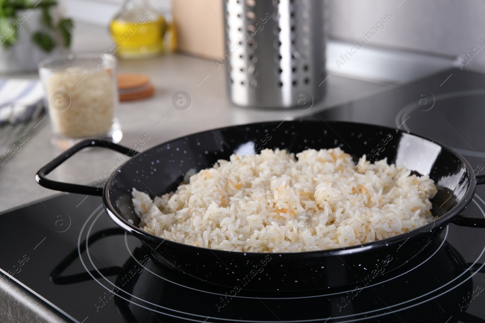 Photo of Cooking tasty rice on induction stove in kitchen, closeup