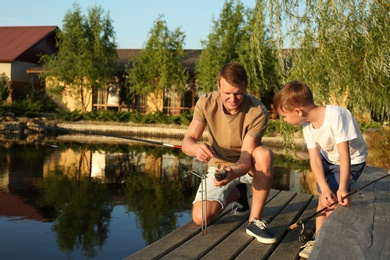 Photo of Dad and son fishing together on sunny day