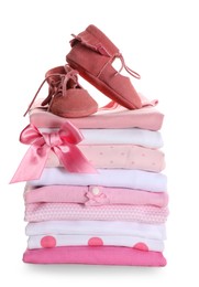 Stack of clean girl's clothes with booties and bow on white background