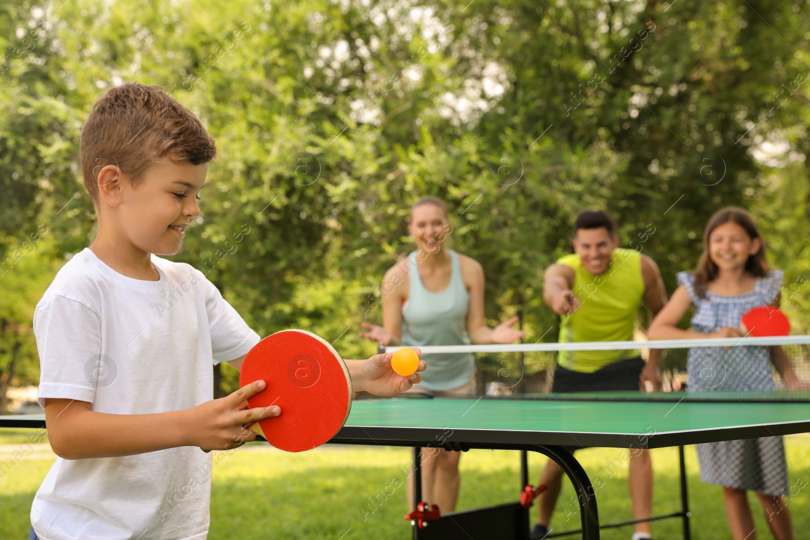 Photo of Happy family playing ping pong in park