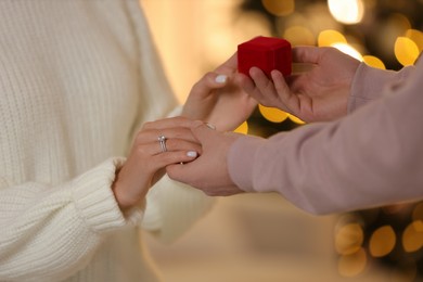 Photo of Making proposal. Woman with engagement ring and her fiance holding hands against blurred lights, closeup