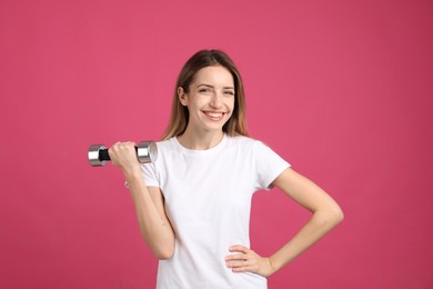 Photo of Woman with dumbbell as symbol of girl power on pink background. 8 March concept