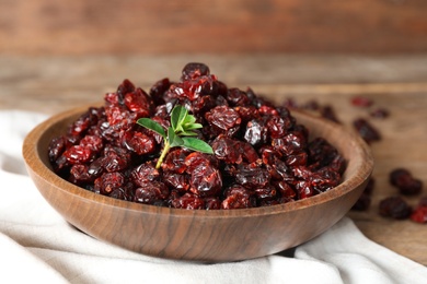 Photo of Dried cranberries in bowl on wooden table, closeup