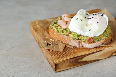 Delicious sandwich with guacamole, shrimps and fried egg on light grey table, closeup. Space for text