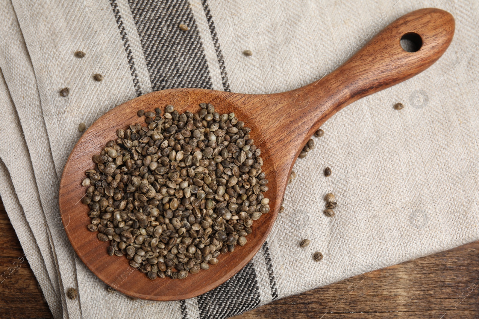 Photo of Wooden spoon with organic hemp seeds on table, flat lay