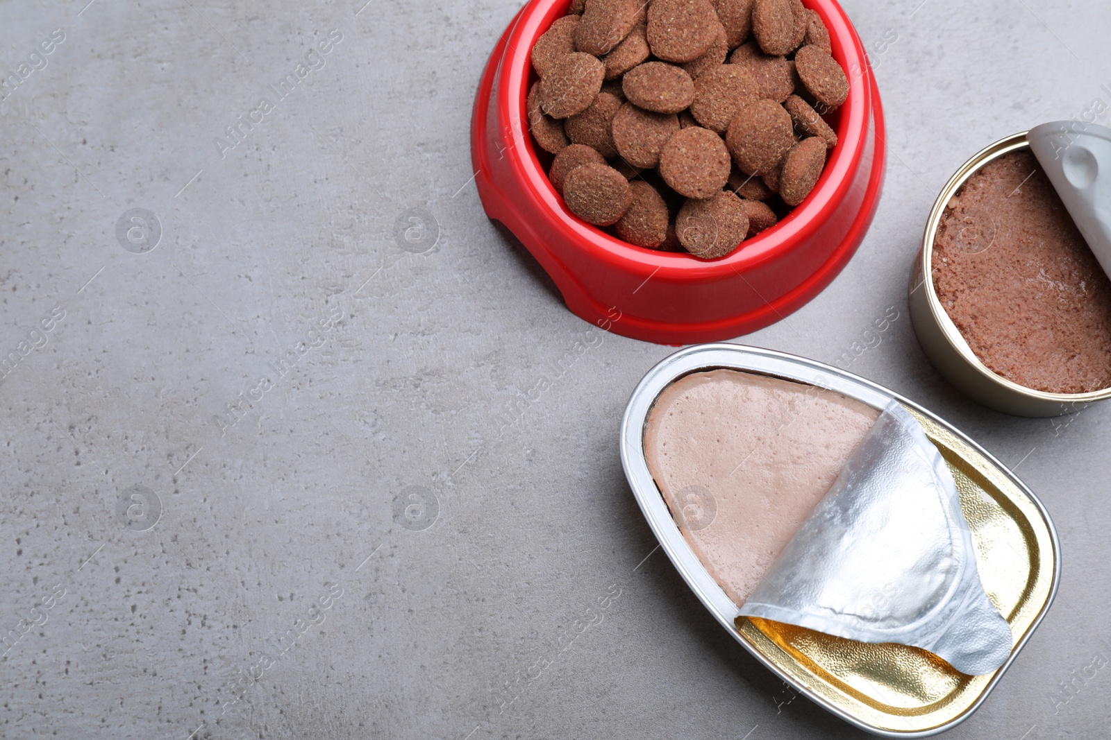 Photo of Wet and dry pet food on grey table, flat lay. Space for text