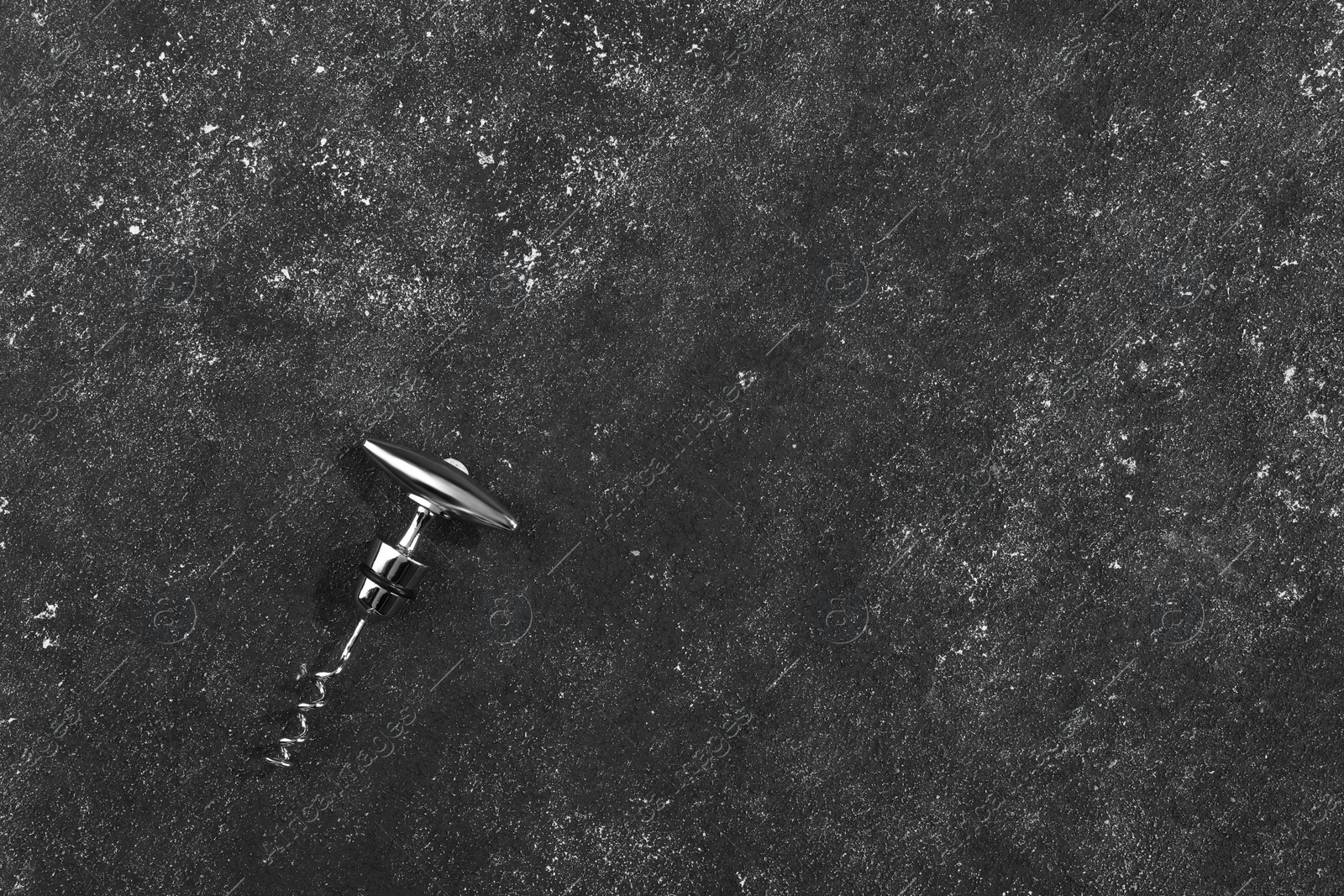 Photo of One corkscrew on grey textured table, top view. Space for text