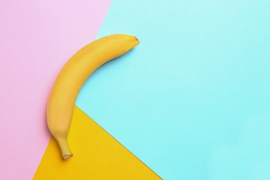 Photo of Ripe tasty banana on color background, top view with space for text