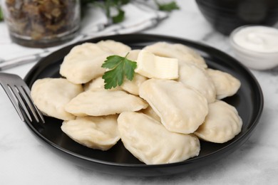 Photo of Delicious dumplings (varenyky) with tasty filling, butter and parsley served on white marble table, closeup
