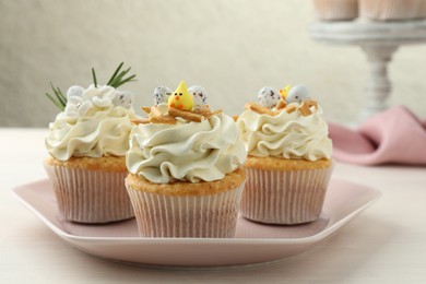 Photo of Tasty Easter cupcakes with vanilla cream on light wooden table