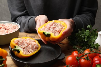 Woman making stuffed peppers with ground meat at wooden table, closeup