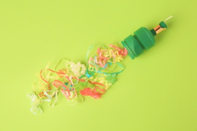 Colorful serpentine bursting out of small party popper on green background, flat lay