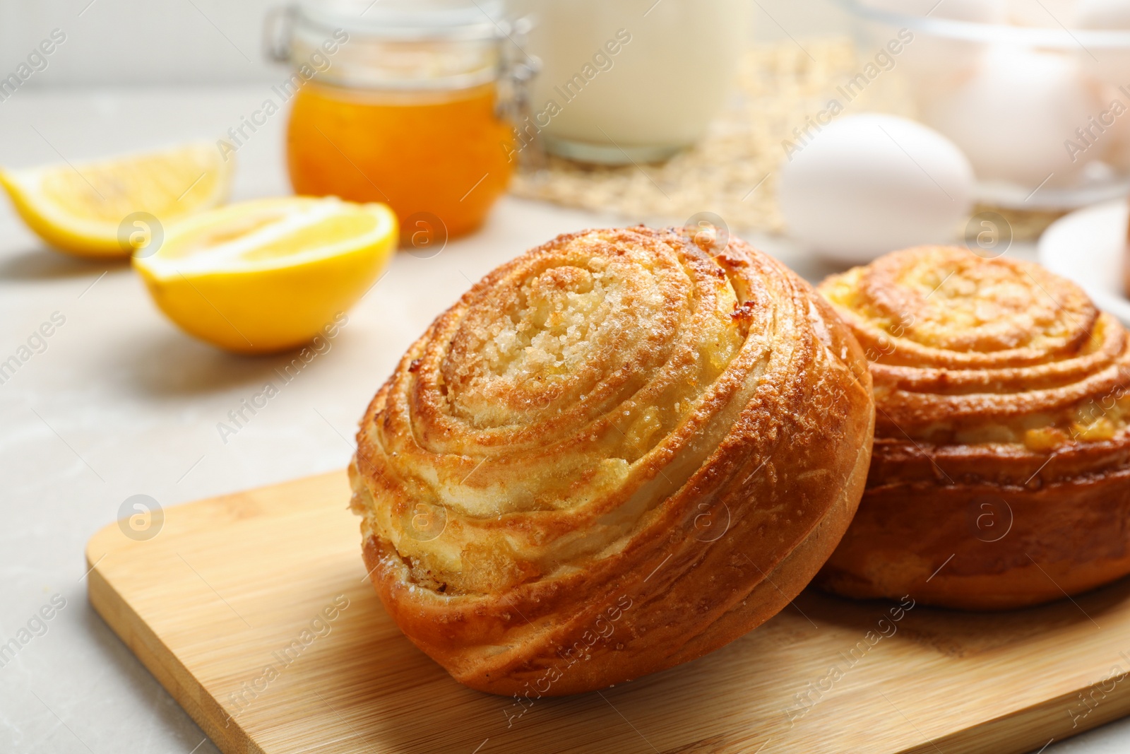 Photo of Wooden board with tasty buns on table, closeup. Fresh from oven