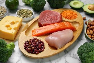 Photo of Different fresh products on white marble table. Sources of essential amino acids