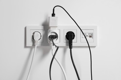 Photo of Many different electrical power plugs in sockets on light wall