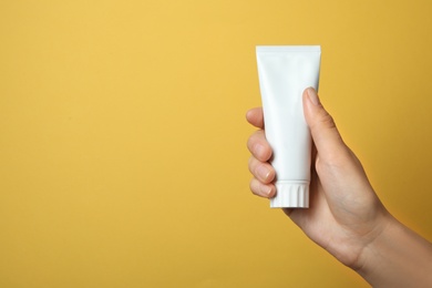 Photo of Woman holding blank toothpaste tube on color background. Space for text