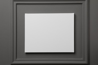 Blank canvas hanging on grey wall, space for text