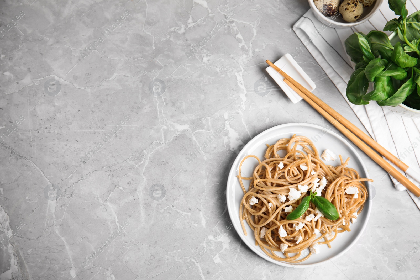 Photo of Tasty buckwheat noodles with chopsticks on light grey table, flat lay. Space for text