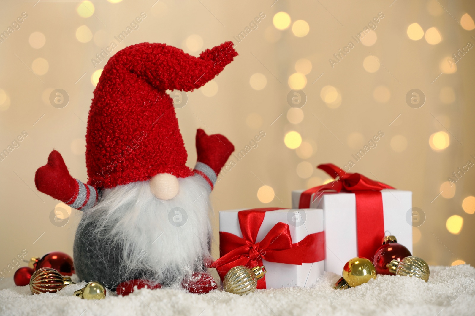 Photo of Cute Christmas gnome, gift boxes and festive decor on snow against blurred lights